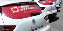 Domaine aide et soins à domicile. Autocollant perforé avec logo de la-solution.ch sur vitre arrière du véhicule professionnel, création graphique bureau région Yverdon-les-bains